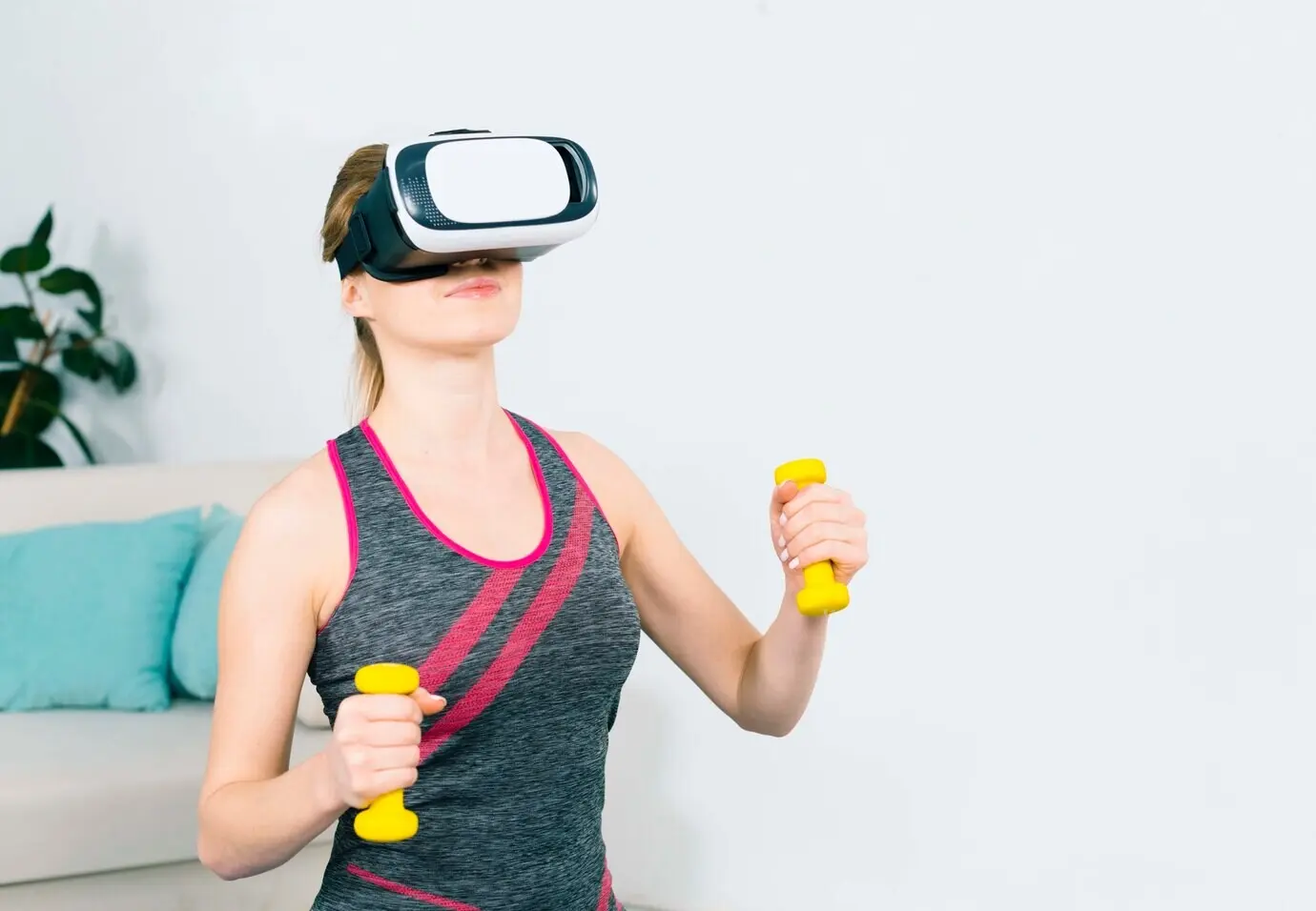 Nahaufnahme einer jungen Frau, die ein Virtual-Reality-Headset benutzt und mit gelben Hanteln trainiert.
